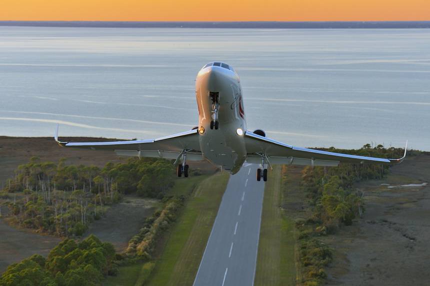 A plane flying over the ocean with its landing gear down.